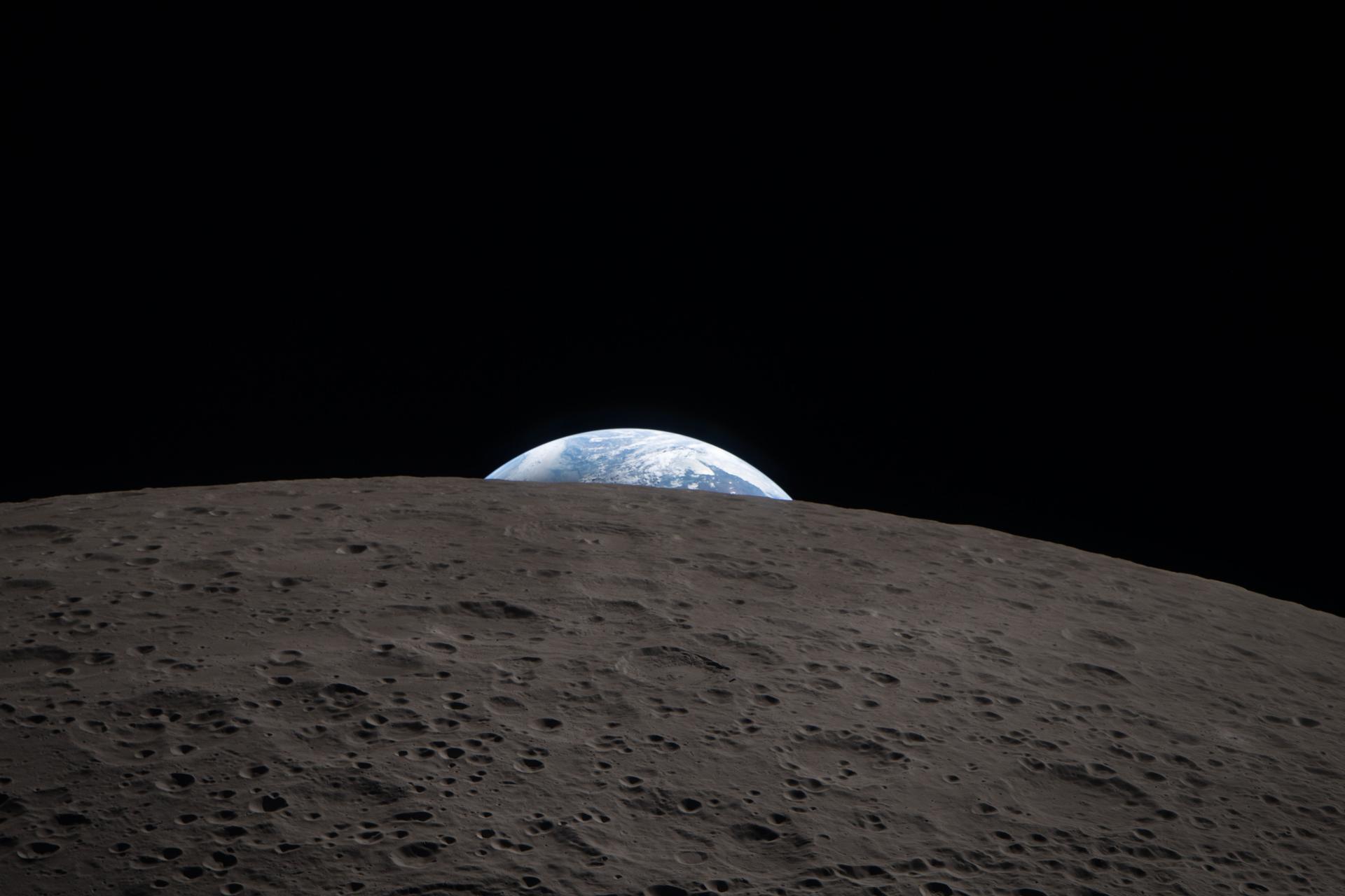 Earth rising above the lunar horizon viewed from the Moon's surface